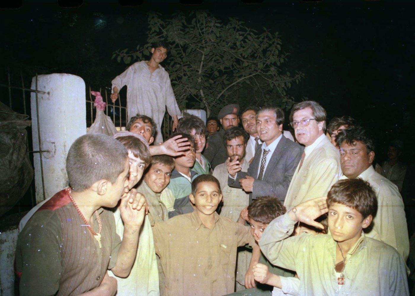 A large crowd of boys and young men gathers around the team near a park gate after nightfall. A large crowd of boys and young men gathers around the team near a park gate after nightfall.